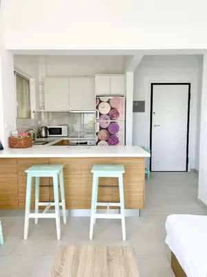 a kitchen with a counter and two stools in it at Saronida beach apartments kids and pets friendly in Saronida