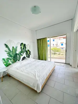 a bedroom with a large white bed with plants at Saronida beach apartments kids and pets friendly in Saronida