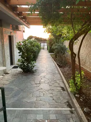 a stone walkway in a garden with a pergola at Saronida beach apartments kids and pets friendly in Saronida