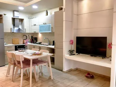 a kitchen and dining room with a table and a tv at A7 Beauty Vouliagmeni Apt in a unique Spot in Athens