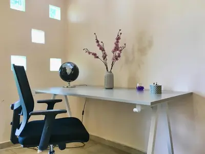 a white desk with a chair and a vase of flowers at A7 Beauty Vouliagmeni Apt in a unique Spot in Athens