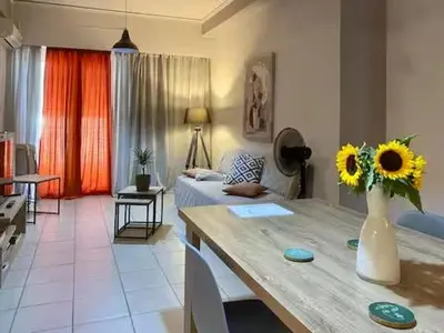 a living room with a table with a vase of sunflowers at Bright & Cozy 1BR in Athens city center in Athens