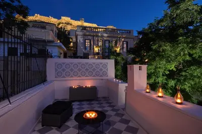a balcony with a table and lights in front of a building at Muazzo Plaka Homes, Upper Home with Balcony & Ground Home No Balcony, by ThinkVilla in Athens