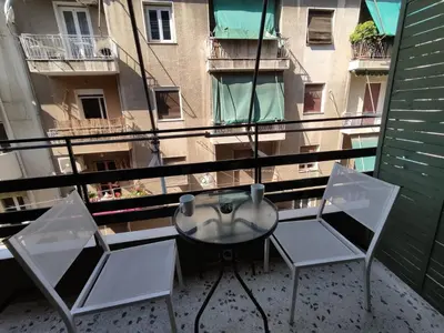 a balcony with two chairs and a table and a building at PURE URBAN PREMIUM METRO AGIOS NIKOLAOS in Athens