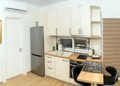 a kitchen with white cabinets and a table and chairs at Modern studio Chiou in Athens
