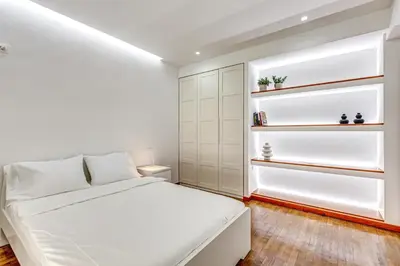 a white bedroom with a bed and shelves at EvZin Homes Athens NEa Smyrni in Athens