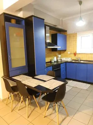 a kitchen with blue cabinets and a table and chairs at LG apartment bnb in Athens