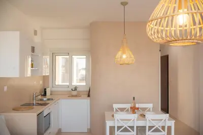 a kitchen with white cabinets and white chairs and lights at Private Jacuzzi & Acropolis View - The Suite in Athens