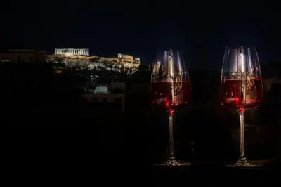 two glasses of red wine with a city in the background at Private Jacuzzi & Acropolis View - The Urban Loft in Athens