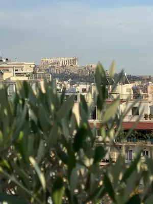 a view of a city from behind some buildings at Private Jacuzzi & Acropolis View - The Urban Loft in Athens