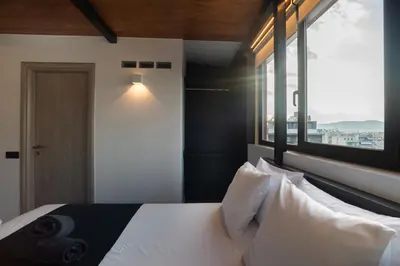 a bedroom with a white bed with a large window at Private Jacuzzi & Acropolis View - The Urban Loft in Athens