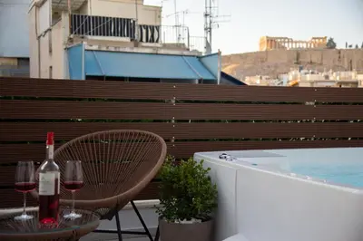 a patio with a table and two glasses of wine at Private Jacuzzi & Acropolis View - The Athenian Loft in Athens