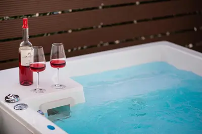 two glasses of red wine and a bottle of champagne in a tub at Private Jacuzzi & Acropolis View - The Athenian Loft in Athens