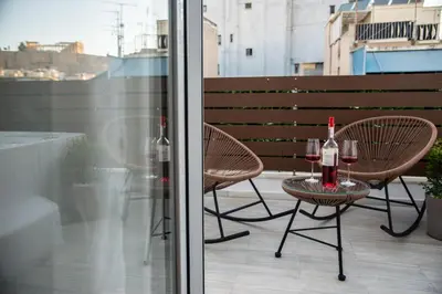 a table and two chairs with wine glasses on a balcony at Private Jacuzzi & Acropolis View - The Athenian Loft in Athens