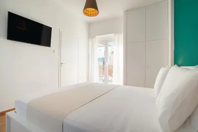 a white bedroom with a white bed and a television at Private Jacuzzi & Acropolis View - The Athenian Loft in Athens