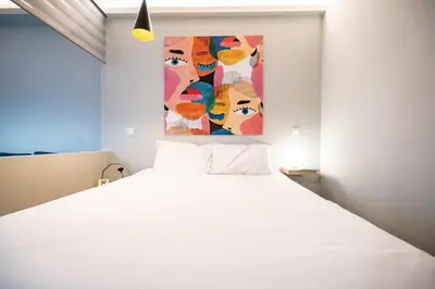 a bedroom with a white bed and a painting on the wall at Evaggelismos m station studio for 3 pers by MPS in Athens
