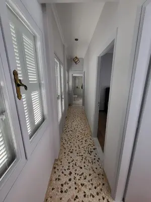 a hallway with white walls and windows and a tile floor at Maria's Maisonette in Athens