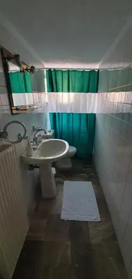a bathroom with a sink and a green shower curtain at Glyfada-Elliniko in Athens