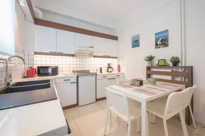 a kitchen with white cabinets and a table with chairs at Noho apartments x Koukaki dikaiou 6 in Athens