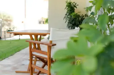 a wooden table and a white chair next to a table at Vasiliki's House in Porto Rafti