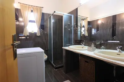 a bathroom with two sinks and a shower and a toilet at Secret Garden Home Lagonissi Attiki in Foinikiá