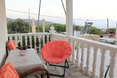a balcony with a table and a red chair at Secret Garden Home Lagonissi Attiki in Foinikiá