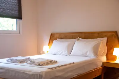 a bedroom with a bed with white sheets and pillows at Serenity - Brand New Apt Near Athens Int Arpt in Spáta