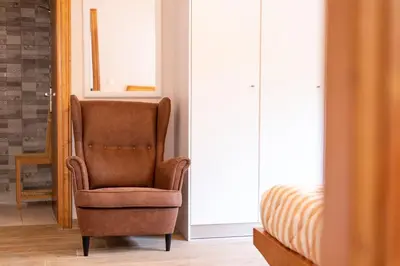 a brown chair sitting in a room next to a bed at Serenity - Brand New Apt Near Athens Int Arpt in Spáta