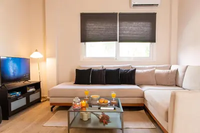a living room with a couch and a tv at Serenity - Brand New Apt Near Athens Int Arpt in Spáta