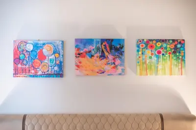 three paintings on a wall above a couch at Panathenaic Stadium By Greece Apartments in Athens