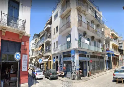 a tall white building with cars parked on a street at Apartment 55 in Athens