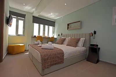 a bedroom with a large bed with two orange chairs at IPELHOME-Avissinias Boutique Apartments in Athens