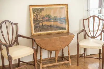 a table with two chairs and a painting on the wall at Athenean Classic Apartment at Acropolis Museum & Metro in Athens