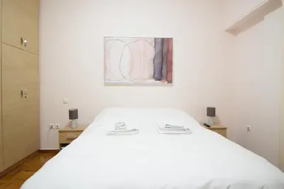 a bedroom with a white bed and a painting on the wall at acropolis super cosy apartment in Athens