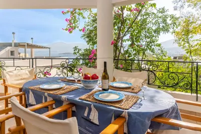 a table on a balcony with a bottle of wine at Porto sea view house - 15min from Athens airport - AC - WIFI - PARKING in Porto Rafti