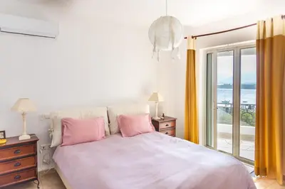 a bedroom with a bed with pink pillows and a window at Porto sea view house - 15min from Athens airport - AC - WIFI - PARKING in Porto Rafti