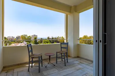 two chairs and a table on a balcony with windows at Spacious apartment in Kavouri in Athens