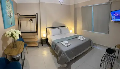 a bedroom with a bed and a table and a television at Theo Appartement Athen in Athens