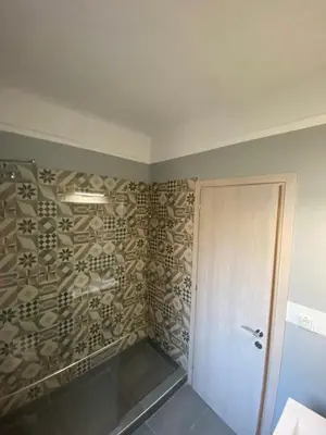 a bathroom with a shower with a stone wall at Theo Appartement Athen in Athens