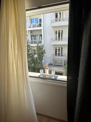 a window with a bottle of wine and glasses on a window sill at G&W Luxury Rooms in Athens