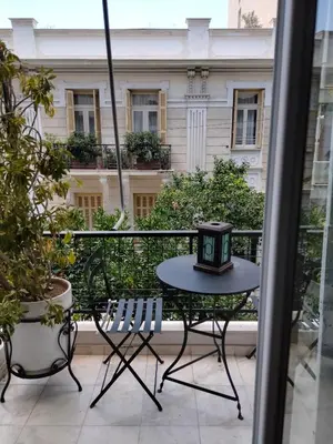 a table and chairs on a balcony with a clock on it at AcropolisCozyStay in Athens