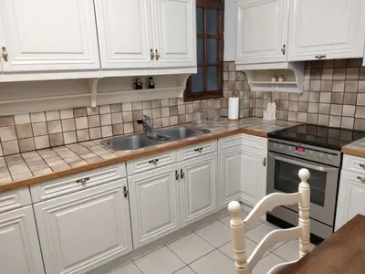 a kitchen with white cabinets and a sink and a chair at AcropolisCozyStay in Athens