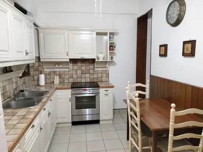 a kitchen with white cabinets and a sink and a table at AcropolisCozyStay in Athens