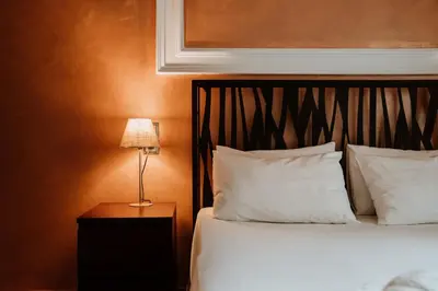 a bed with white pillows and a table with a lamp at Victoria Boutique Studios in Athens
