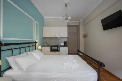 a bedroom with a bed with white sheets and a tv at Victoria Boutique Studios in Athens