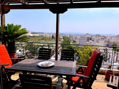 a wooden table with chairs and a plate of food on a balcony at The Best Penthouse View -Sea View Athens Reviera & SNFCC in Athens