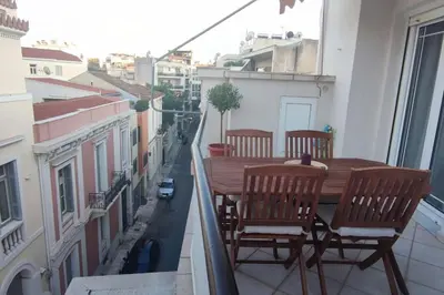 a balcony with a wooden table and chairs on a city street at Plaka's Heart in Athens
