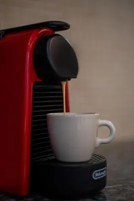 a coffee maker pouring coffee into a white cup at Central Calm Apartment in Athens