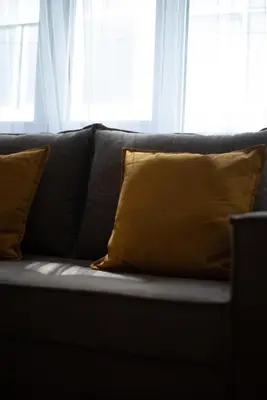 a black couch with yellow pillows in front of a window at Central Calm Apartment in Athens