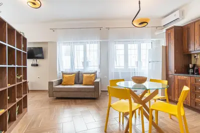 a kitchen and living room with a table and yellow chairs at Central Calm Apartment in Athens